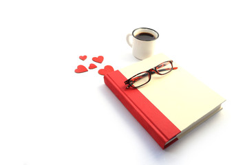 red hardcover book, coffee, reading glasses and hearts on white background with copy space