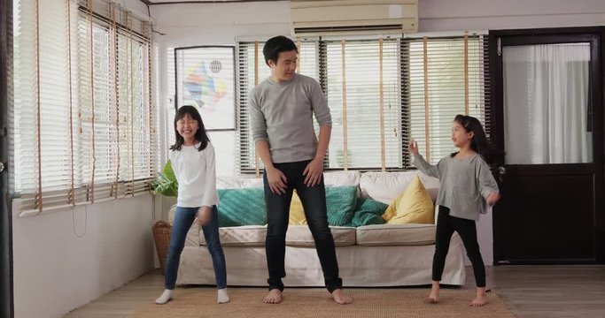 Asian family listening music dancing jumping together. They having fun in modern living room enjoying leisure lifestyle at home together.