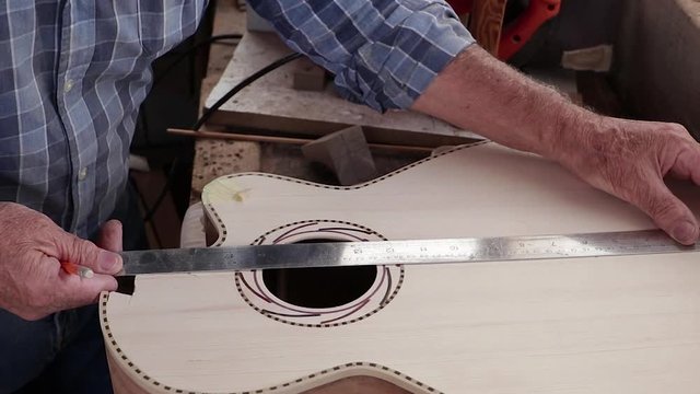 A Guitar Maker Measuring The Wooden Body Of A Guitar - closeup shot