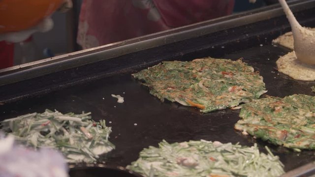 Bindae-tteok in Gukje International Market Busan city. Bindaetteok, fried buchimgae, savory pancake with ground mung beans, vegetables, meat. Korean vendors selling food in street, South Korea