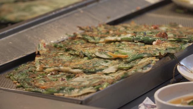 Bindae-tteok in Gukje International Market Busan city. Bindaetteok, fried buchimgae, savory pancake with ground mung beans, vegetables, meat. Korean vendors selling food in street, South Korea