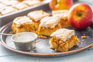 Applie pie cut to cubes with a fresh apple on a vintage tray with a sugar sieve