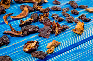 Dried fruits apple, plum, grapes, apricot and pear lying on a wooden surface painted in blue.