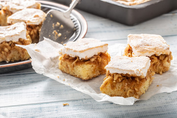 Three cubes of apple pie with a whisked wgg whites topping on a napkin with more pie in the back