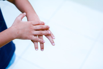 Close up kid is rubbing his hands using hand sanitizer for protective from gems and reduce infectious agents on the hands. Selective focus, simple and clean image and noise at image due to low light.