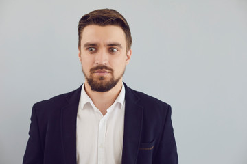 Puzzled insecure man in casual jacket on a gray background. Expression of emotion