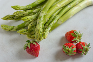 green fresh asparagus with a bunch of healthy strawberries