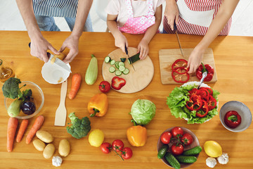 Family cooks fresh vegetables on the table in the kitchen.