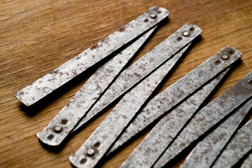 Measuring iron folding meter old, photographed on a shabby wooden surface.