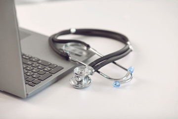 Online doctor call concept. Telemedicine. Stethoscope and laptop on a white table.