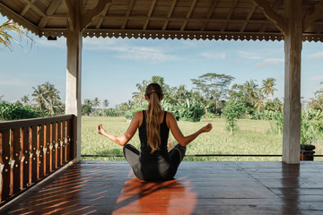 Young Caucasian playing and pose Yoga on the floor with nature rice field and blue sky background,...