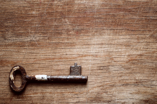 Iron old key, photographed on a shabby wooden surface.