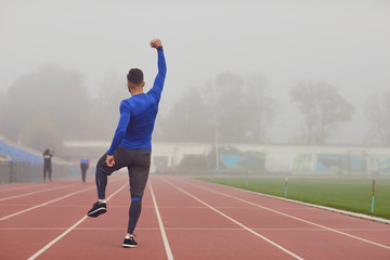 Obraz premium The guy the athlete raised his hands up at the stadium in the fog.