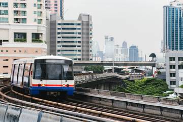 Naklejka premium Skytrain arriving to the station. Turn. Close up. Skyscrapers on the background.