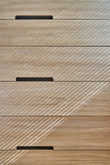 Wooden cupboard with drawers in daylight. Modern wooden furniture. Wooden texture