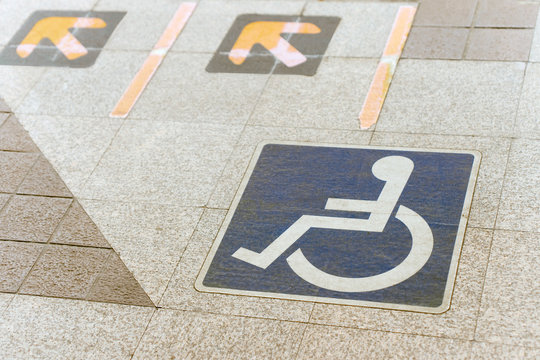 Wheelchair access sign on the floor. Railway station. Blue sign, yellow arrows.