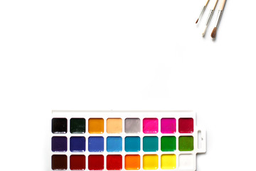 A palette of eighteen-color watercolors and paintbrushes on a white background with space for text.