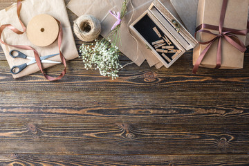 Craft paper and tools for creating and decorating gift packaging. There is cardboard, brown ribbons and rope on a wooden table. Concept of a creative approach to creating gift packaging with handmade.