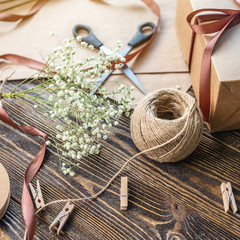 Craft paper and tools for creating and decorating gift packaging. There is cardboard, brown ribbons and rope on a wooden table. Concept of a creative approach to creating gift packaging with handmade.