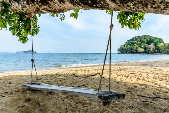 Rustic wooden swing hanging from a tree on a beach with sea views on an island in Phang-Nga Bay, near Phuket, Thailand