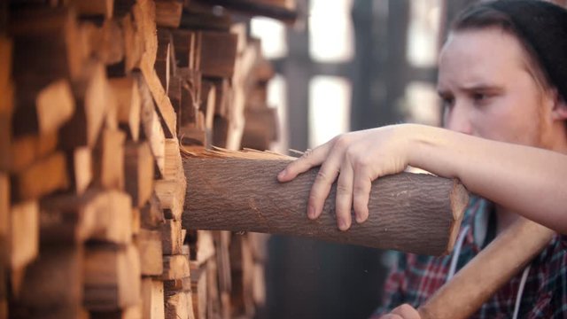 Young man woodcutter with ax puts in the log in the stand