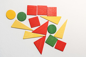 Different colorful shapes wooden on white background. Geometric shapes red, green, yellow colors, top view. Concept of geometry. Copy space. Children educational logical task. Flat lay.