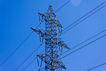 High voltage electric tower against a bright blue sky.