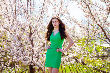 Young girl posing near blossom cherry tree with white flowers