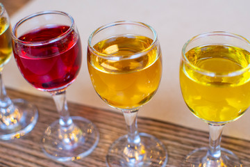 Colourful set of alcoholic cocktails in shot glasses shooters on wooden table for an alcoholic party. Set of traditional liquors and tinctures.