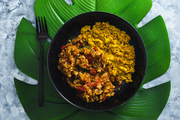 plant-based food, vegan scrambled tofu with mediterranean veggies and potatoes on leaf-shaped placemat