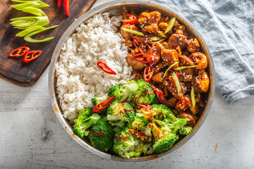 Top view of a teriyaki chicken with rice, broccoli and chilli on a white table