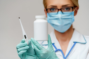 medical doctor nurse woman wearing protective mask and rubber or latex gloves - holding can of medicine and thermometer