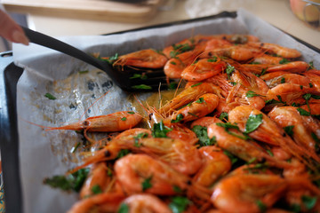 Fresh boiled prawns with coriander on protvin. The cook puts a spatula on juicy seafood. Delicious dish for gourmets
