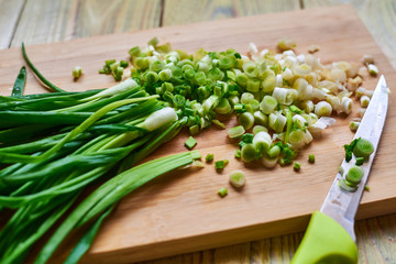 chopped fresh green onions on a cutting wooden board.