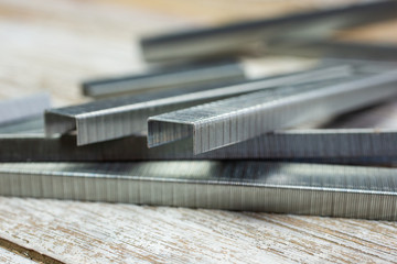 A macro closeup view of several strips of staples, on a wooden surface.