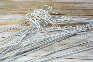 A closeup view of a pile of white metal hangers on a wooden surface.