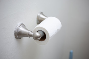 A view of a half used roll of toilet paper on a wall dispenser, in a bathroom setting.