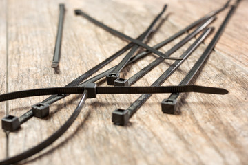 A closeup view of several zip ties, on a wooden surface. © DAVID