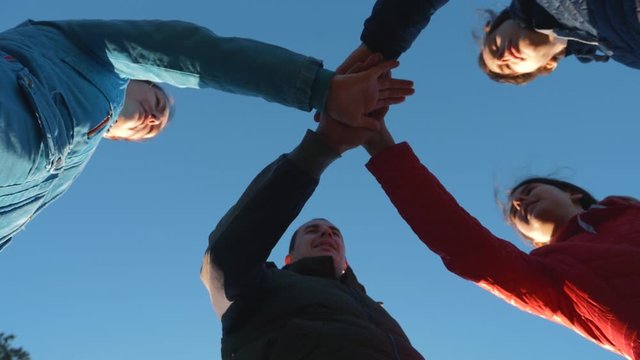 Close-up view from the bottom of the folding hands together. A happy family puts their hands together, demonstrating unity and teamwork.