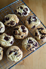 Homemade baked chocolate chip soft cookies cooling on a cooling rack. On a wooden background. Natural light.