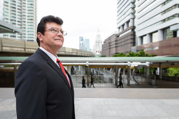 Mature handsome businessman in front train station at Bangkok city