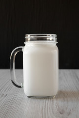 Coconut milk in a glass jar mug, side view.