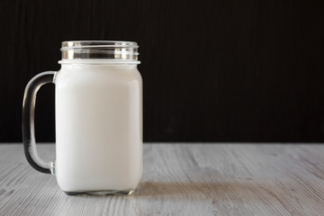 Coconut milk in a glass jar mug, side view. Space for text.