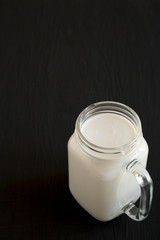 Coconut milk in a glass jar mug, side view. Copy space.