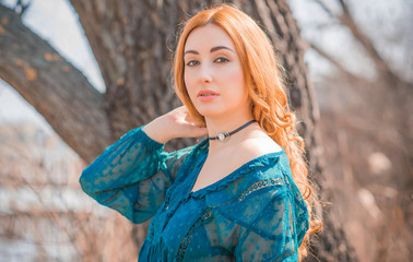 Fototapeta premium Nice redhead curly woman in blue blouse, hairstyle for girls