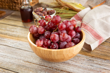 A view of a bowl of red table grapes, in a still life setting.
