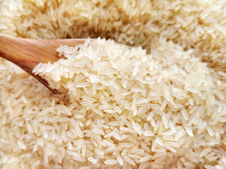 Parboiled rice on wood spoon.  Selective focus.  Copy space is on the blurry parts of photo. 