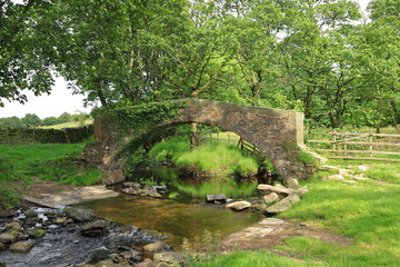 Fototapeta na wymiar A stone bridge crosses a stream in the West Yorkshire countryside close to the village of Haworth in northern England.