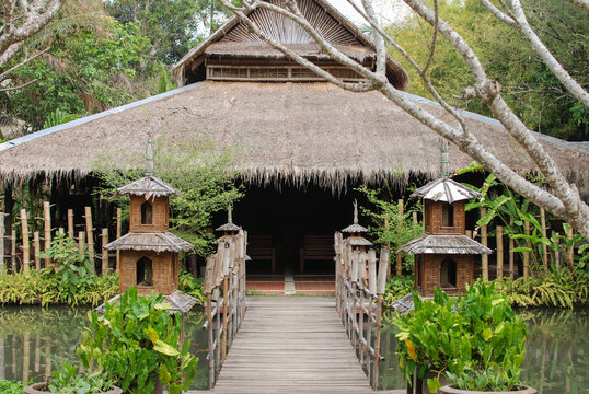 View from the entrance of a hut with thatched roof surrounded by a garden with a pond
