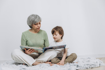 A little boy and his grandmother are having fun together against a light background